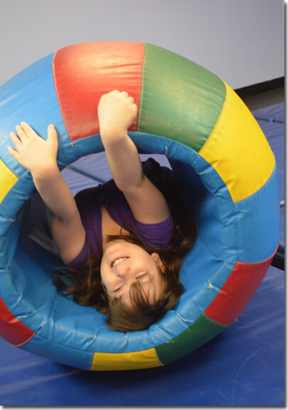 Kid playing in a gym rolling tire