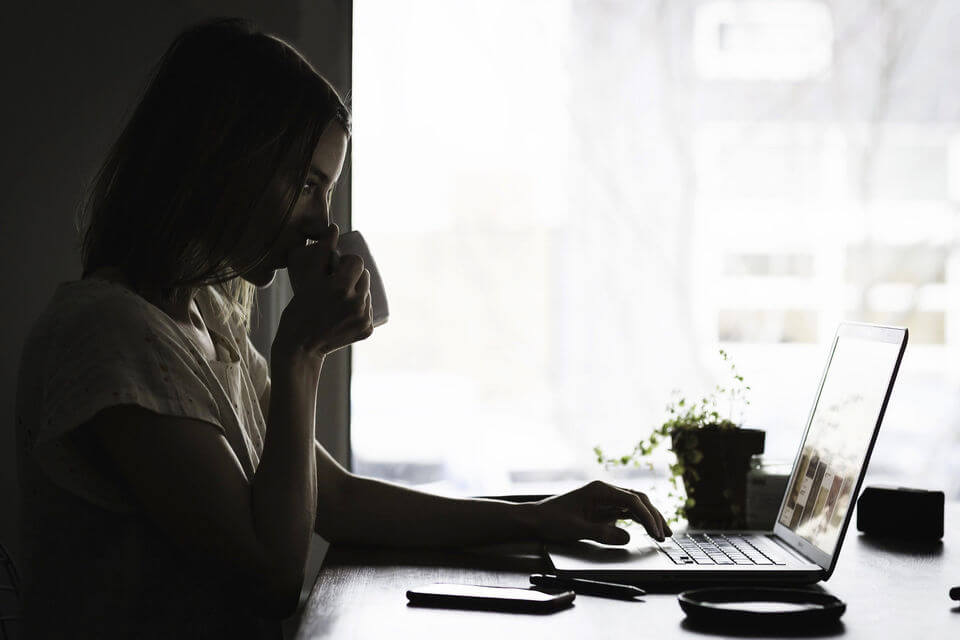 Woman at laptop drinking from mug