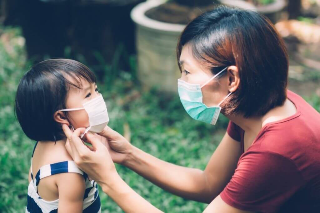 Masked woman putting mask on child