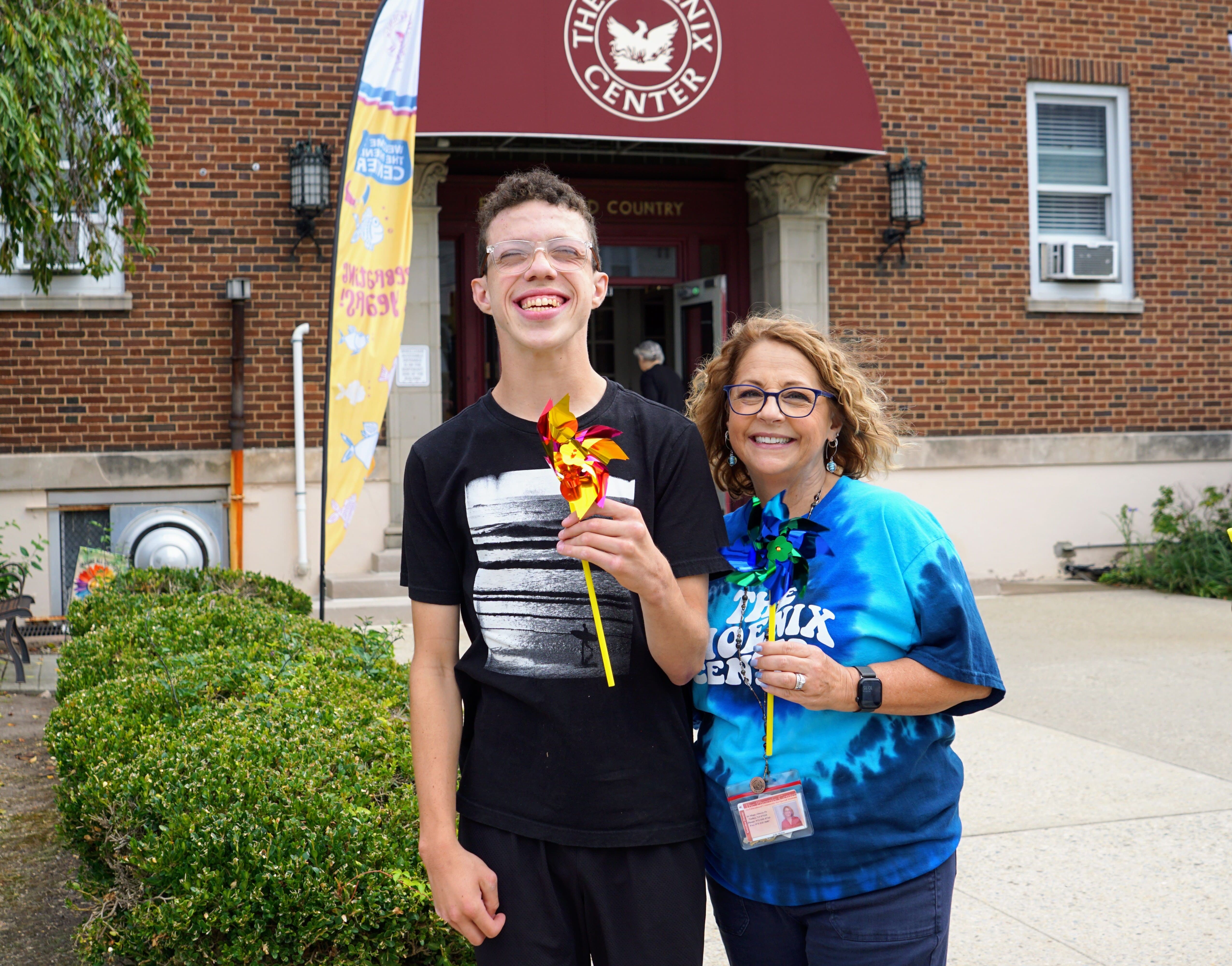 TPC's Executive Director, Julie Mower, and student Owen posing in front of the entrance to The Phoenix Center