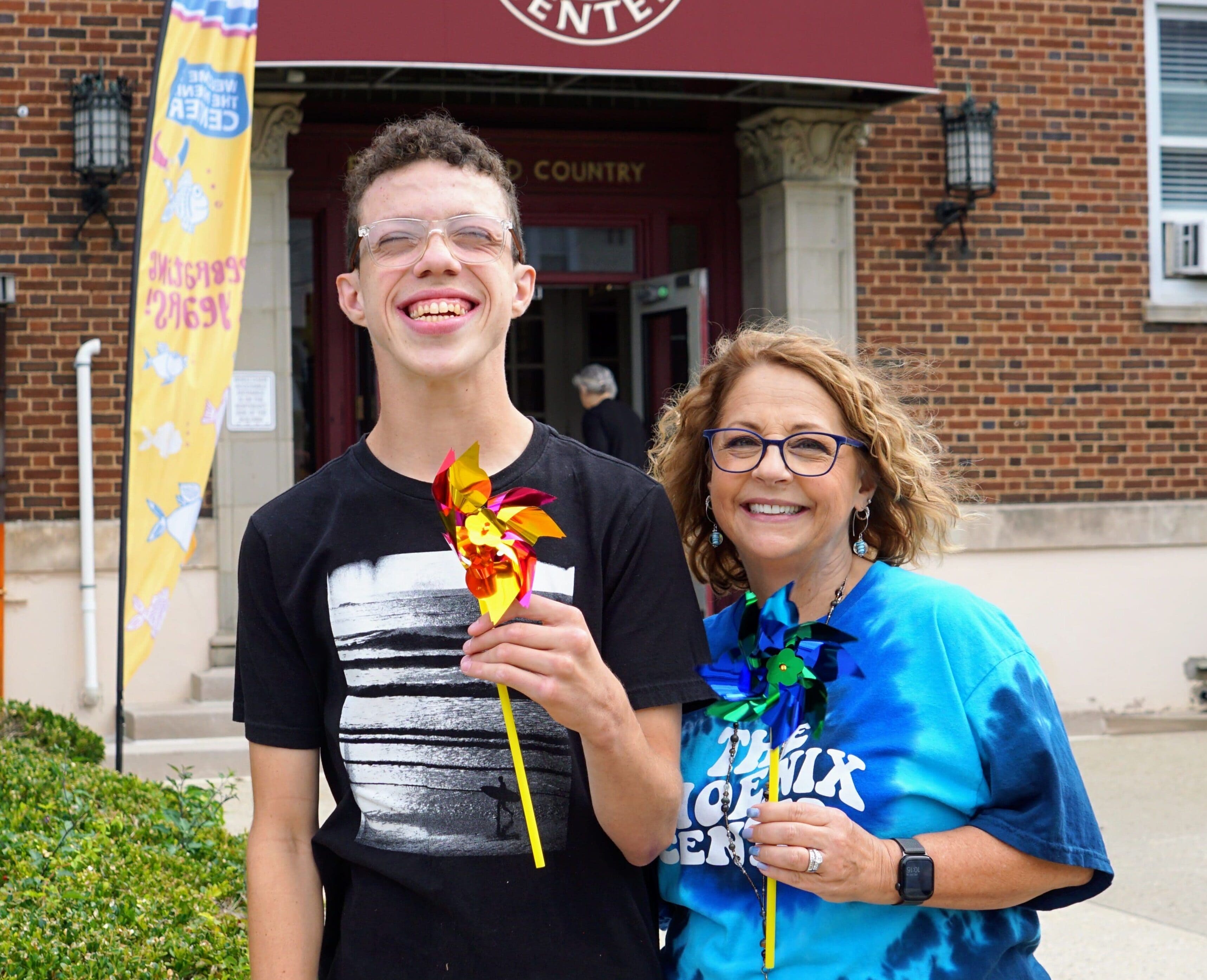 TPC's Executive Director, Julie Mower, and student Owen posing in front of the entrance to The Phoenix Center